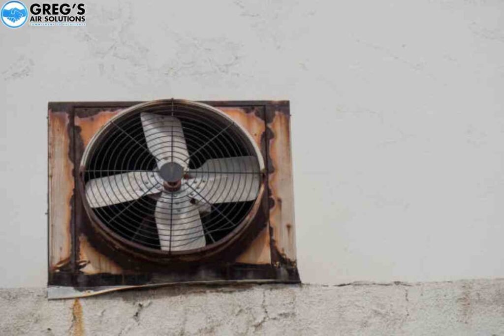 An old, rusty AC fan motor mounted on a wall, showcasing its weathered texture and vintage design.