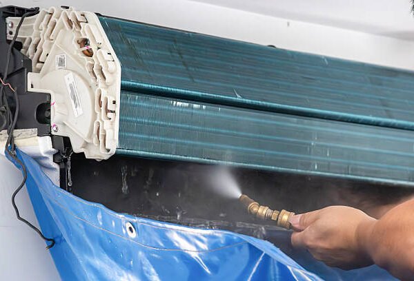 A man cleaning the coils of a window air conditioner, ensuring optimal performance and efficiency.