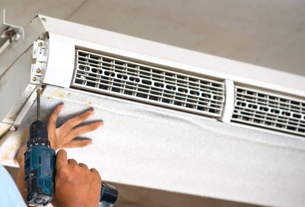 A man works on a mini split air conditioner, ensuring proper installation and functionality of the unit.