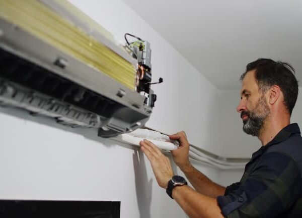 A man is installing a mini split air conditioner, focused on fixing the unit's components.
