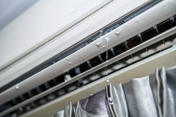 Detailed view of a window AC unit with water leaking from it, suggesting an issue with drainage or condensation.