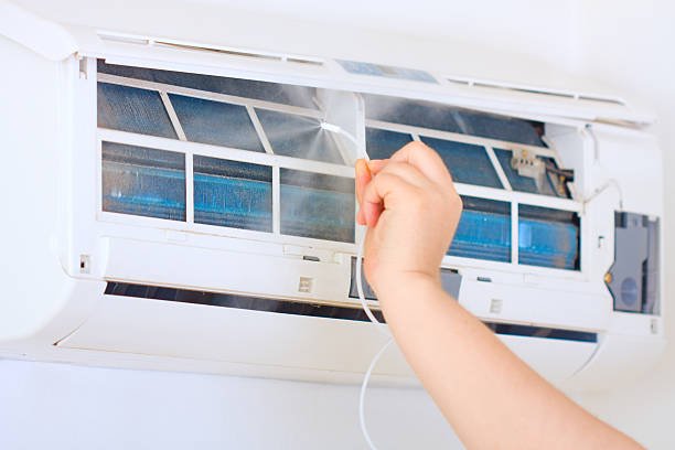 An HVAC technician is carefully performing AC coil cleaning, ensuring the air conditioning unit runs efficiently and delivers clean, cool air throughout the space.