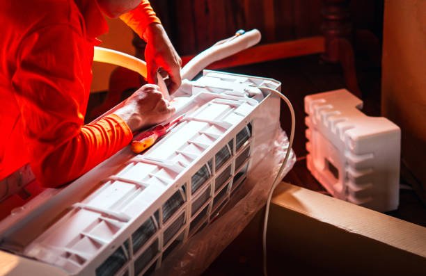 A man is installing a mini split air conditioner, focused on fixing the unit's components during a mini split AC installation in Deerfield Beach FL.