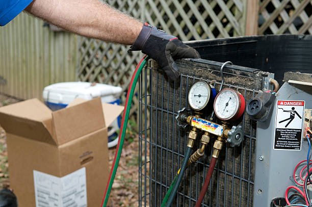A man adjusts an air conditioner during an HVAC tune-up, ensuring optimal performance and efficiency.