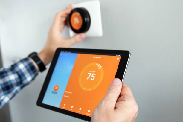 Individual controlling a Nest thermostat via a tablet, focusing on troubleshooting the device.