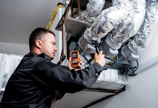 A man checks the temperature of a duct using a digital thermometer during an HVAC installation.