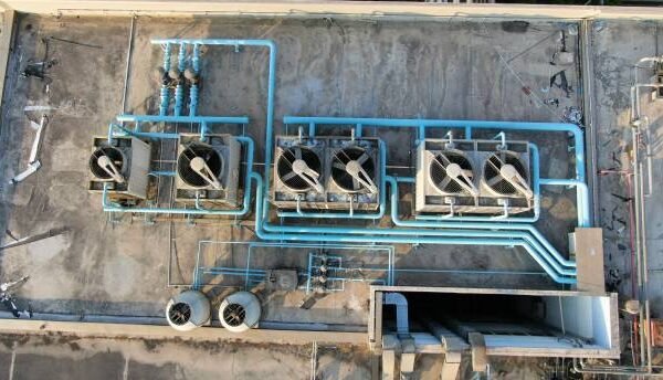  Aerial perspective of a large building featuring numerous pipes, highlighting HVAC installation work.