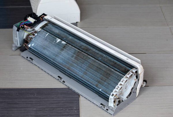 Detailed view of a malfunctioning air conditioner, highlighting cracks and internal parts of the HVAC unit.