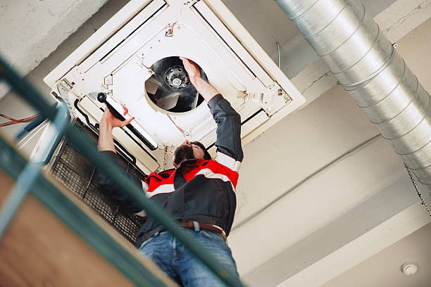 An HVAC contractor is fixing an air conditioning unit in a commercial building.