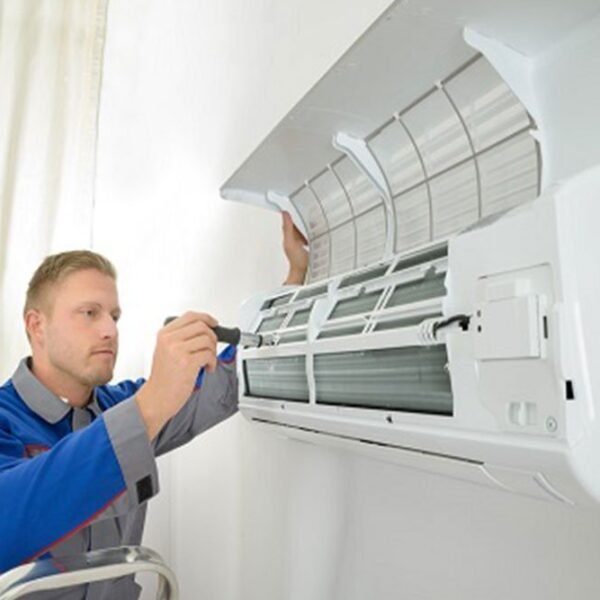 A worker is doing regular Hvac maintenance plan on the indoor unit of an air conditioner