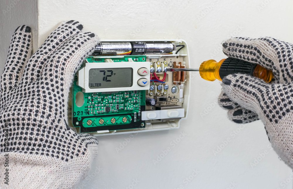 Smart thermostat installation and repair being performed on modern home HVAC system