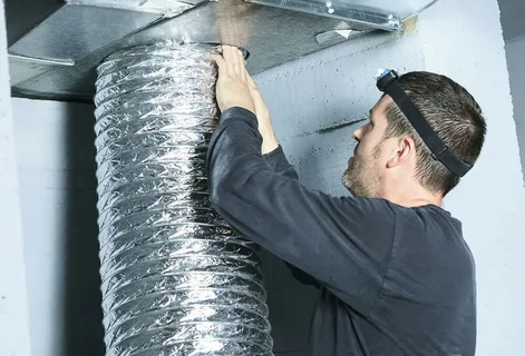 HVAC technician performing a flexible duct installation in a residential ceiling