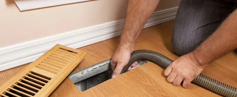 Professional HVAC installer securing overhead air vents during a Duct Installation service